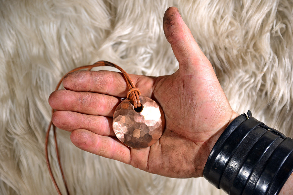 Photograph of hand forged bronze pendant on leather necklace. Jewellery.
