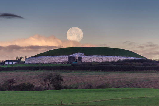 The full moon in winter time sets behind Newgrange as viewed from the south bank of the river Boyne