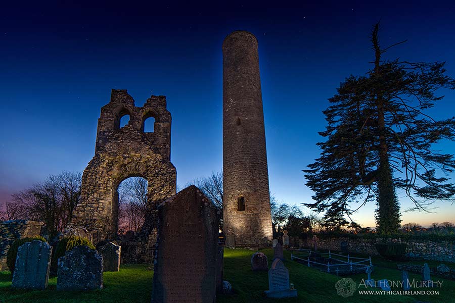 Donaghmore Round Tower, near Navan, Co. Meath, is located not far from the Boyne River. The tower in the 18th century had a conical top, with four windows underneath, near the top of the tower. A local landowner made alterations in 1841, presumably removing the cone-shaped top and blocking up any openings. A cross fragment in the National Museum is probably from Donaghmore.