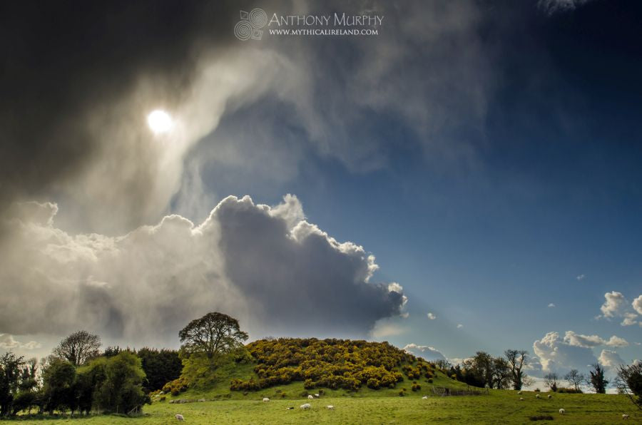 The great mound of Dowth emerges from the darkness as the sun appears from behind a shower cloud.