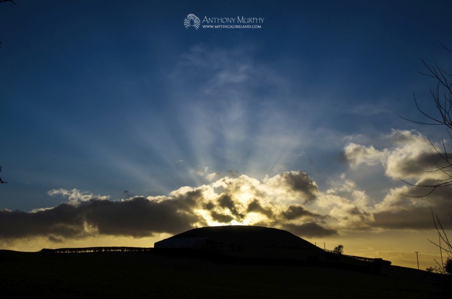 Sunbeams emerge from behind Newgrange